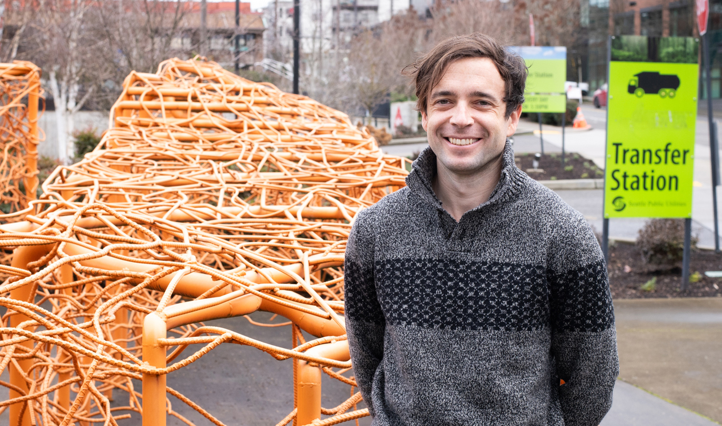 Nick Logler in front of a sign and sculpture at a transfer station
